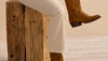 Woman in white denim pants putting on suede cowgirl boots