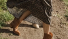 Woman lifting up hem of her floral dress to showcase booties