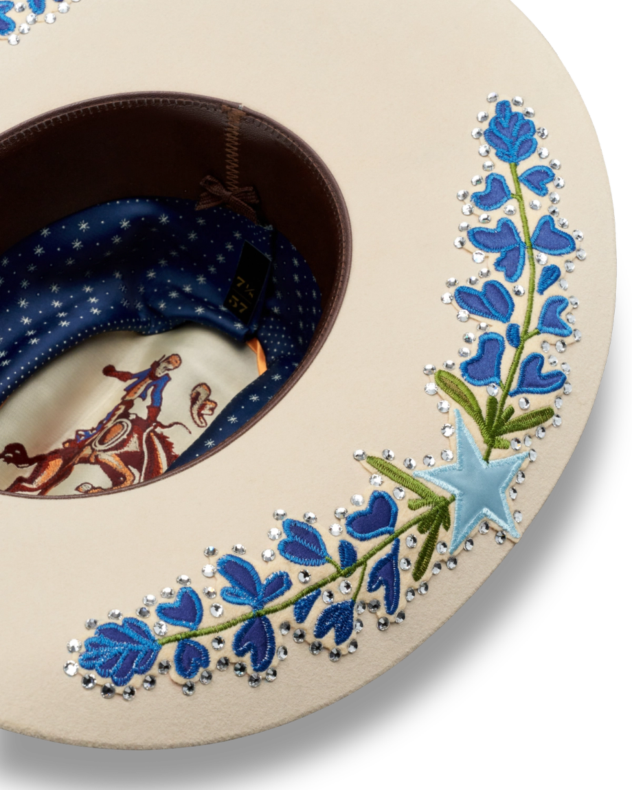Wide-brimmed hat with an embroidered blue flower design and star accents, featuring a detailed cowboy print lining.