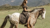 Woman in floral dress and booties riding a horse