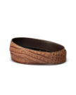 A brown crocodile-embossed leather belt with "Tecovas" stamped on the inner side, displayed coiled on a white background.