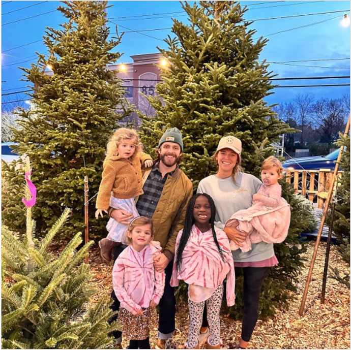 Family standing together by Christmas trees