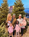 Family standing together by Christmas trees