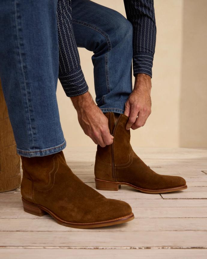 Man bending down seated wearing the Dean in Whiskey. 