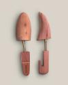 A pair of wooden shoe trees on a light background, one positioned vertically and the other at an angle.
