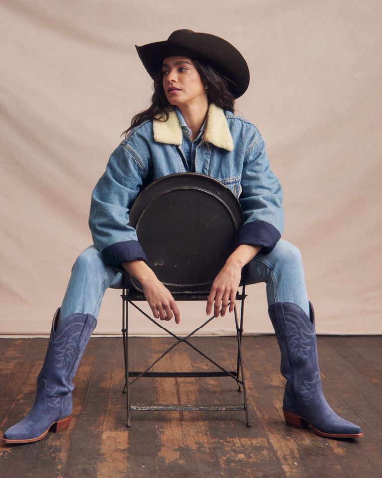 A woman wearing a cowboy hat and blue cowboy boots. (cowboy hat, blue cowboy boots)