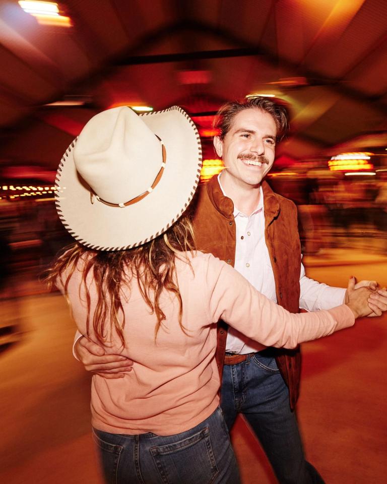 A man and woman dancing in a cowboy hat.
