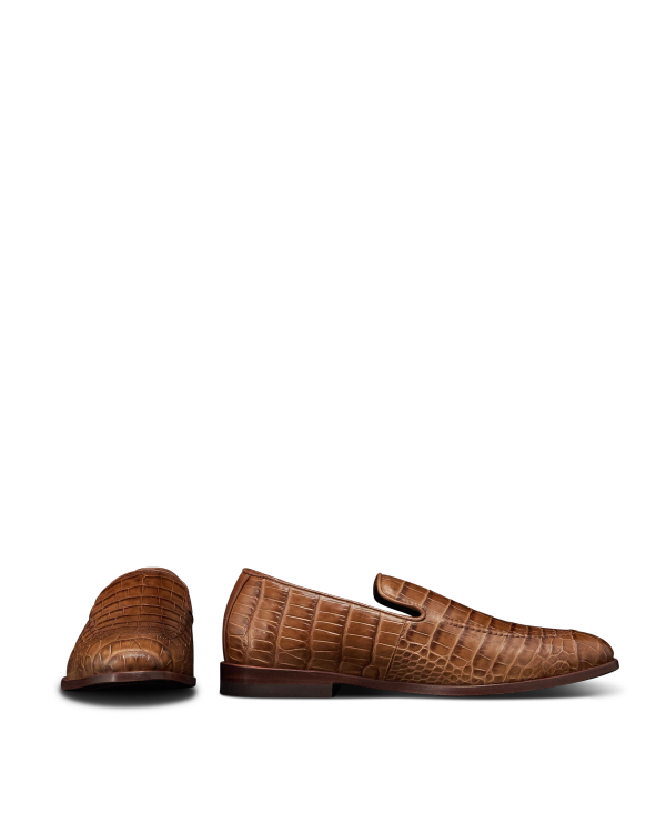 The Bennett in Saddle Alligator. A pair of brown alligator-leather loafers. One shoe shown from the side and one from the front on a white background.