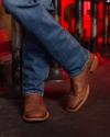 Man wearing boots and jeans with legs crossed