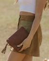 woman holding a leather wristlet pouch in fawn bovine