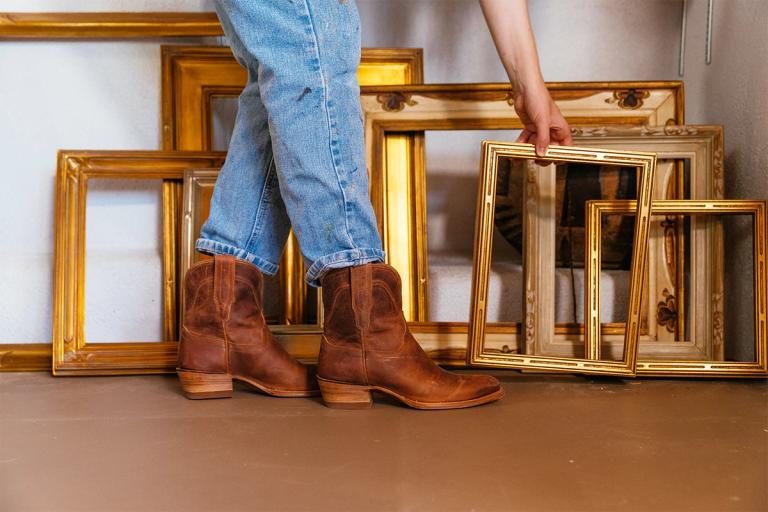 woman in a pair of cowgirl booties holding a gold frame