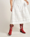 Person wearing a white skirt and red cowboy boots against a neutral background.