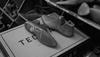 Two shoe lasts rest on a cardboard box labeled "TEC" among other shoe-making materials in a workshop setting.