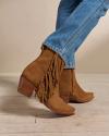 Closeup of woman wearing The Georgia suede fringe bootie in a photo studio