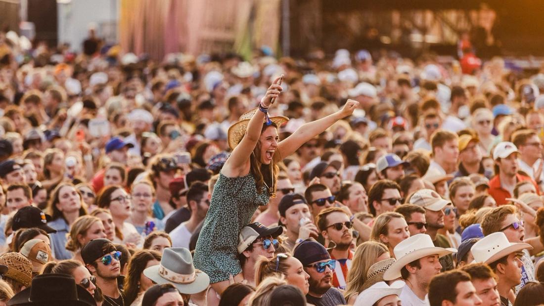 A crowd of concertgoers at a music festival waiting for the main act
