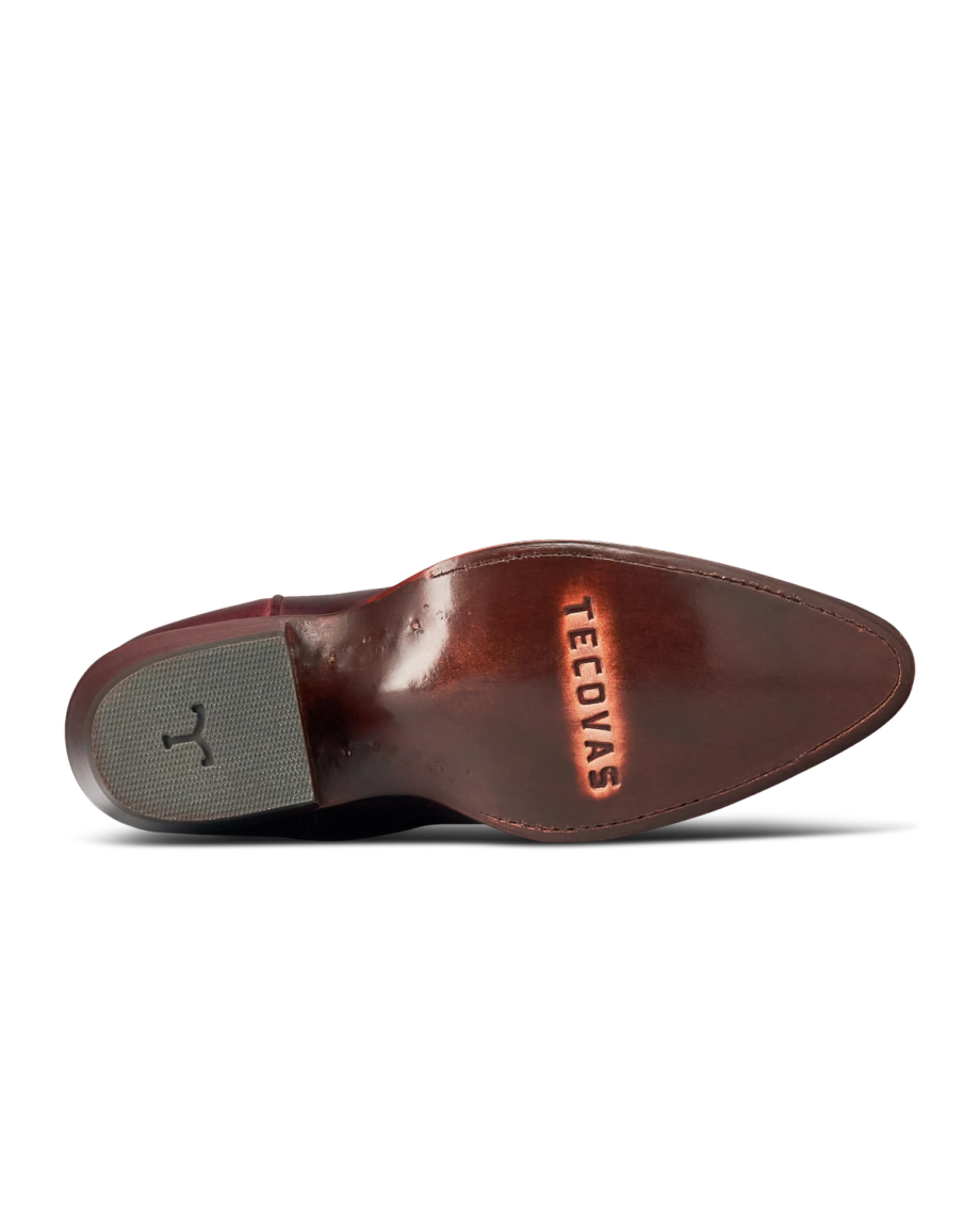 The Abby in Wine Goat. The polished leather sole of a Wine Goat shoe is shown from below, with the word "Tecovas" engraved and a textured gray heel patch visible.