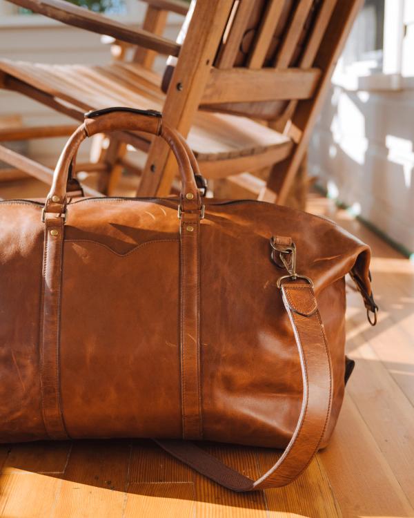 The Bartlett Large Weekender in Cognac resting on a wooden table