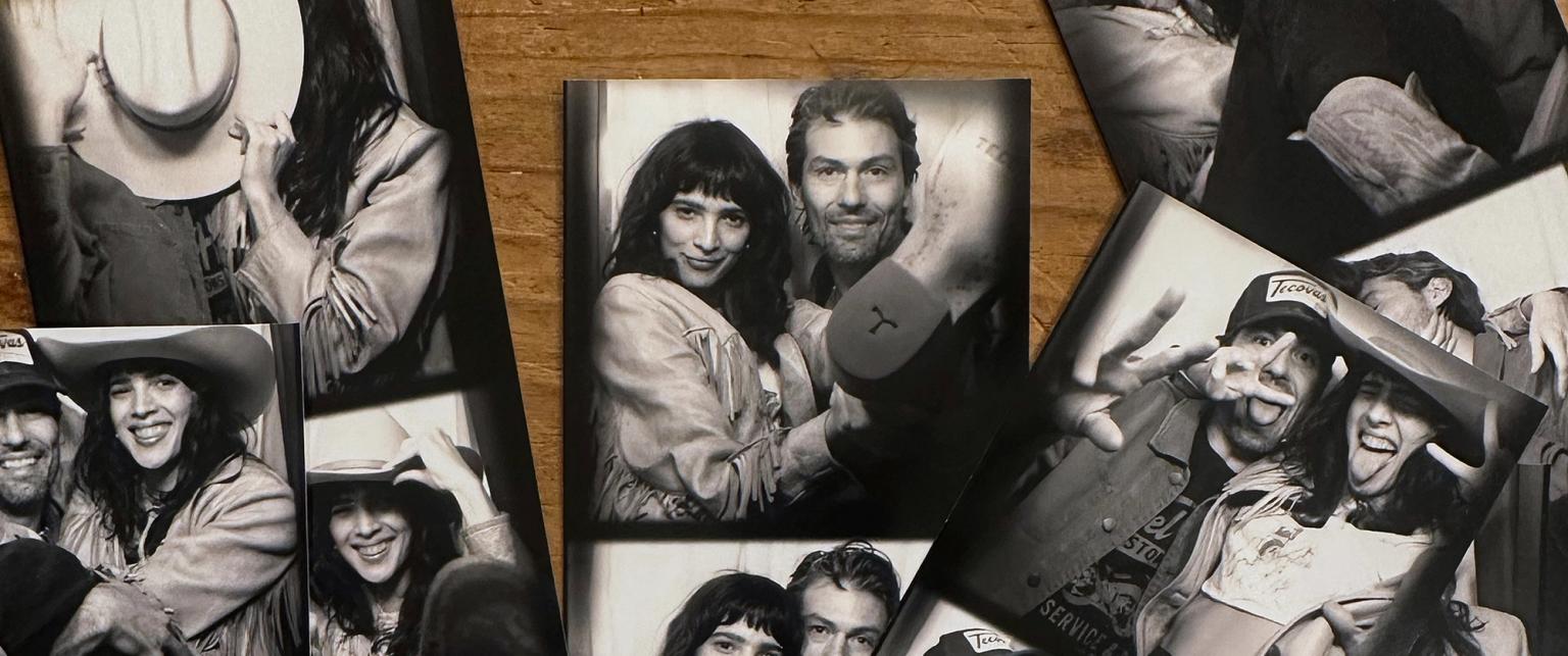 A collection of black-and-white photo booth pictures of a man and a woman posing together, laid out on a wooden surface.
