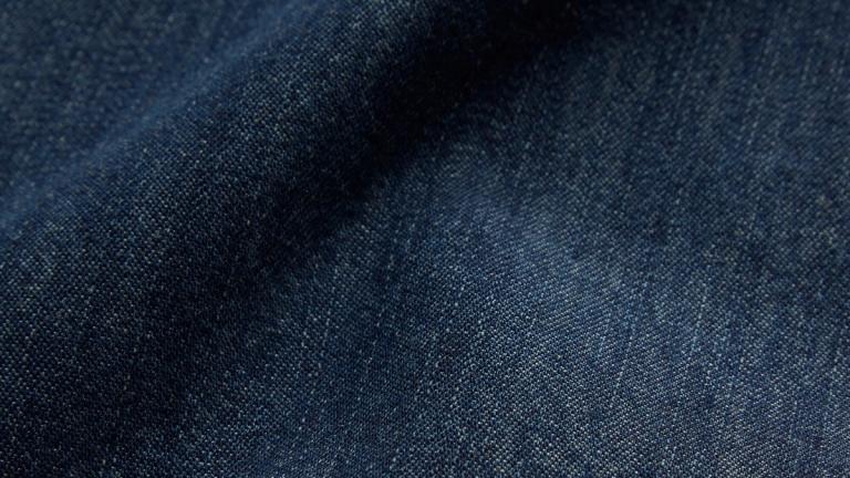 Close-up view of dark blue denim fabric with visible texture and fiber details.