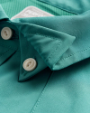 Close-up of a turquoise collared shirt with two white buttons fastened.