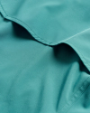 Close-up of a teal fabric with soft folds and visible stitching, showing its smooth texture.