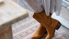 Woman crossing ankles wearing suede boots standing in a kitchen
