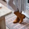 Woman crossing ankles wearing suede boots standing in a kitchen