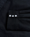 Close-up of a black fabric sleeve with three white buttons aligned in a row.