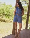Woman in a denim romper and boots standing on a porch