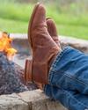 close up picture of Earl scotch brown cowboy boots on a man's feet by a fire