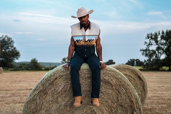 man sitting on a giant hay bail