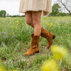 Woman in a field with wildflowers wearing suede boots