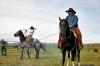 two men on a horse in a corral