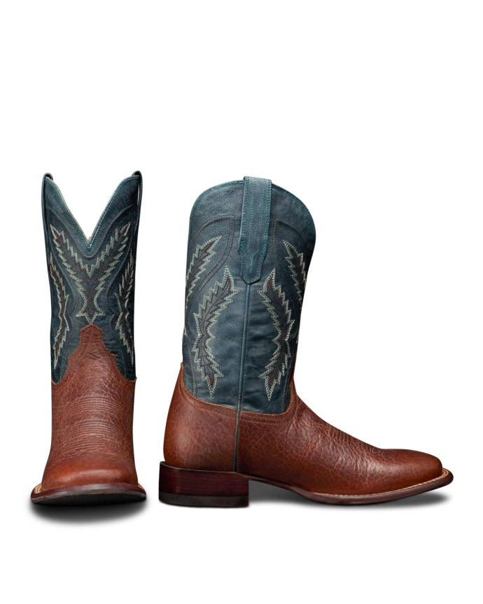 The Doc in Burnt Umber / Blue Cowhide. A pair of cowboy boots with burnt umber cowhide foot and heel, and a blue shaft featuring white decorative stitching. One boot is shown from the front, the other from the side.