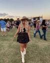 A woman wearing a cowboy hat and boots at a music festival.