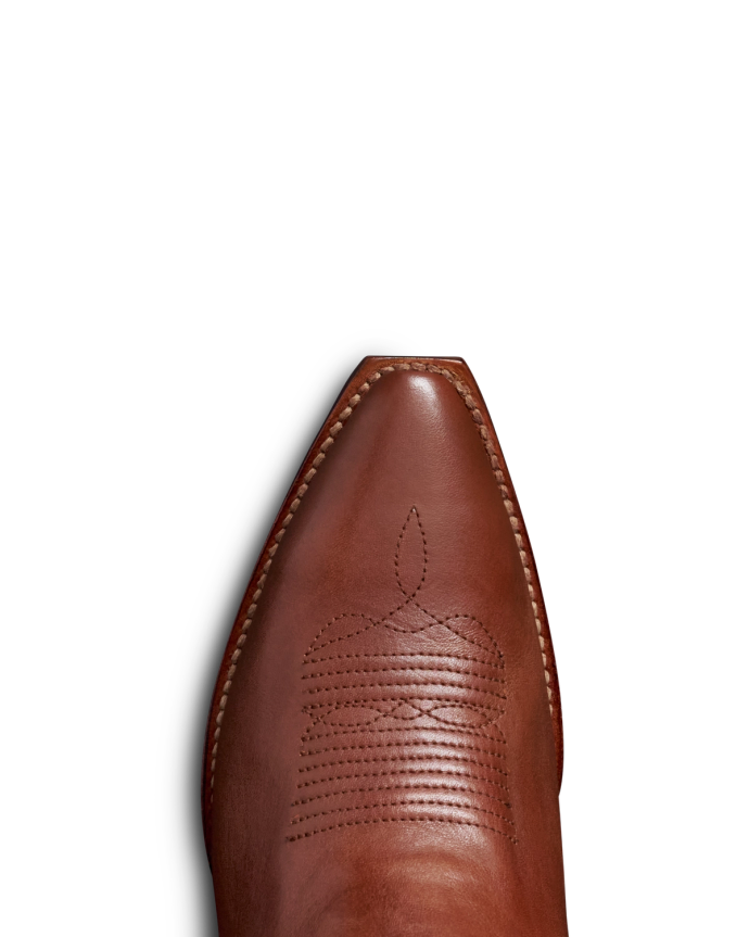 Close-up of a pointed brown leather cowboy boot with intricate decorative stitching on the upper part, set against a black background.