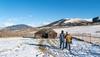 Two people walking through the snow with mountains in the background