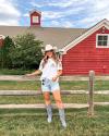 Girl wearing cowgirl boots and cowgirl hat standing near fence