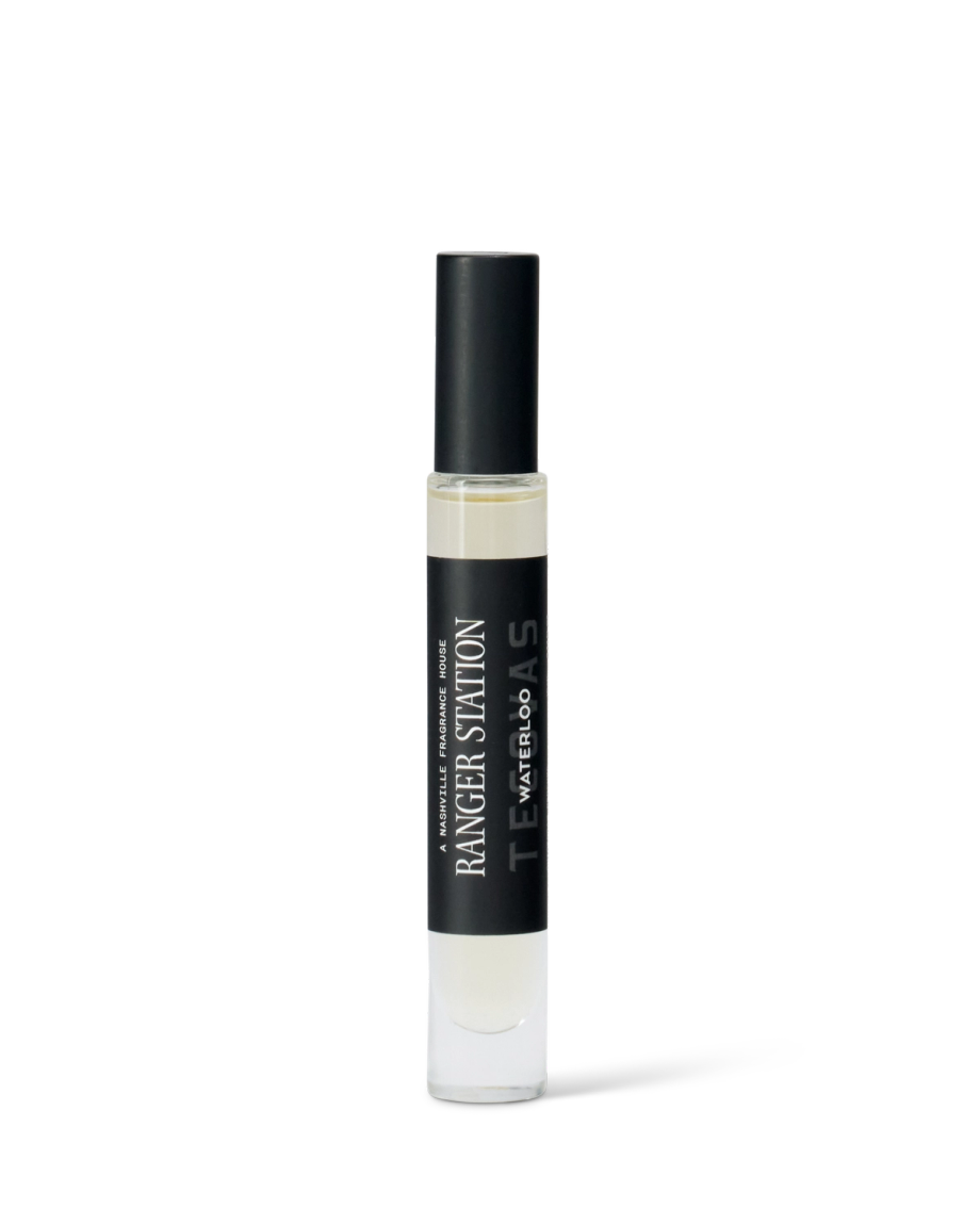 A clear glass perfume spray bottle labeled "Ranger Station Teakwood & Water" with a black cap, shown on a plain white background.