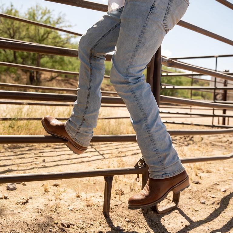 Man on a ranch fence in cowboy boots