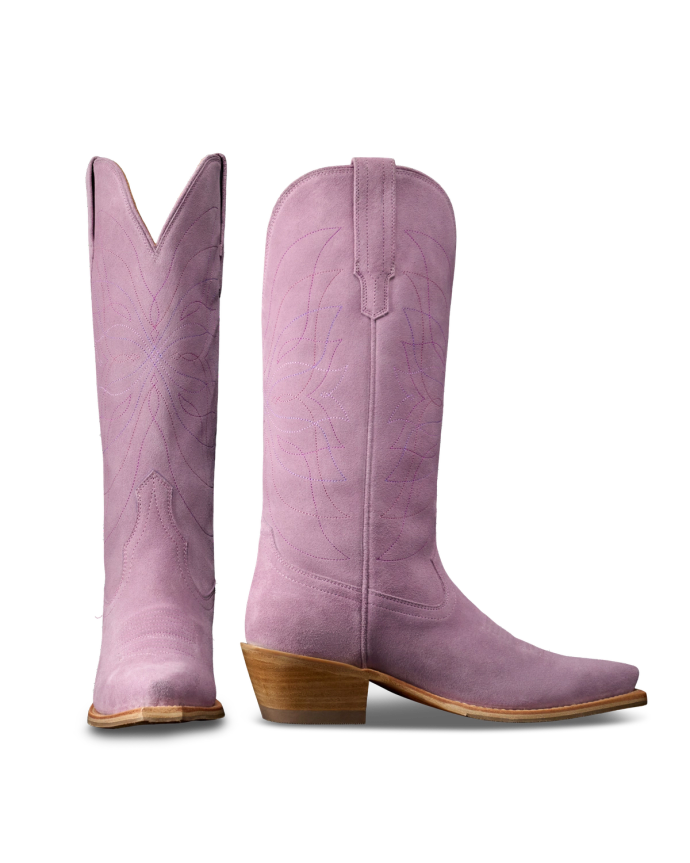 The Annie in Lavender Suede. Pair of tall, light purple Annie Suede cowboy boots with pointed toes, wooden heels, and decorative stitching, shown from side and front angles on a white background.