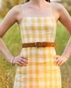 Woman in yellow and white plaid dress with sienna suede belt