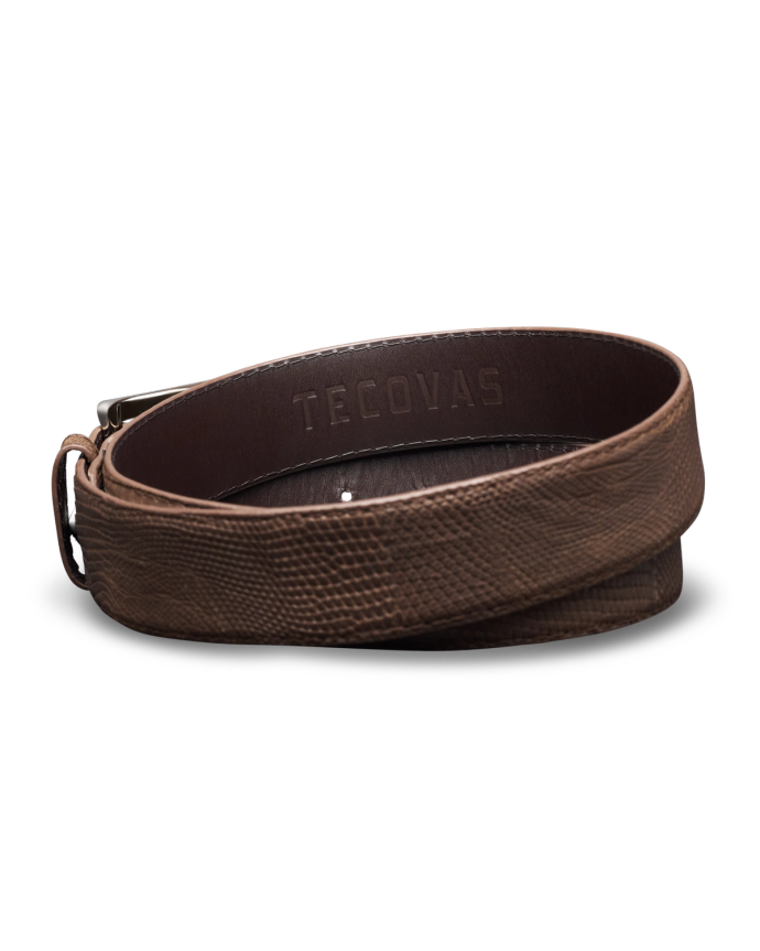 A coiled brown leather belt with textured surface, embossed with the brand name "Tecovas.