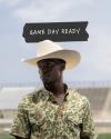 A man wearing a white cowboy hat and camouflage shirt stands outdoors, with text above him that reads "Game Day Ready.