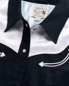 Close-up of a black and white western-style shirt with snap buttons and an embroidered arrow design.