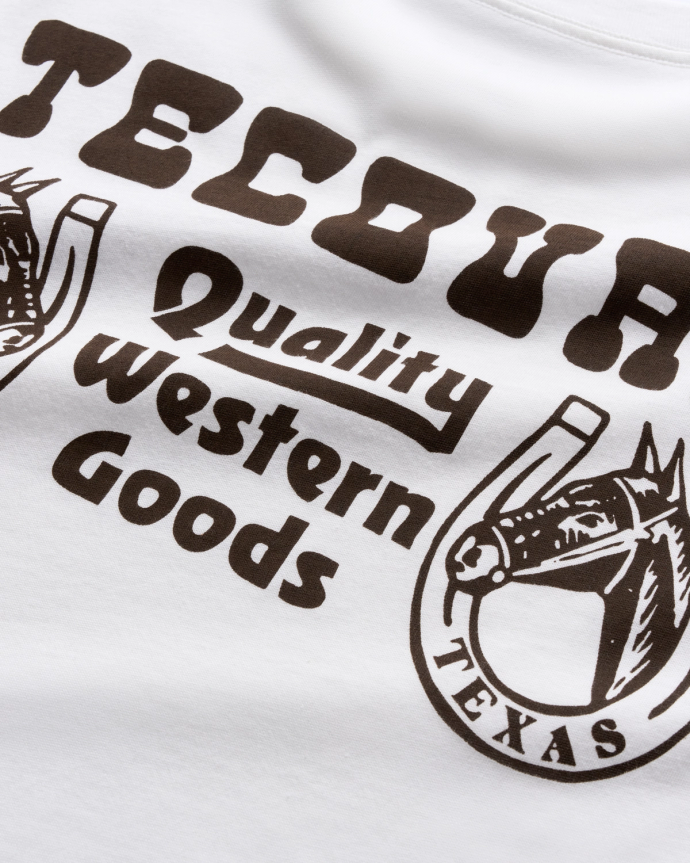 Close-up of a white T-shirt with black print that reads "Tecovas," "Quality Western Goods,” and “Texas," accompanied by horse head and horseshoe illustrations.