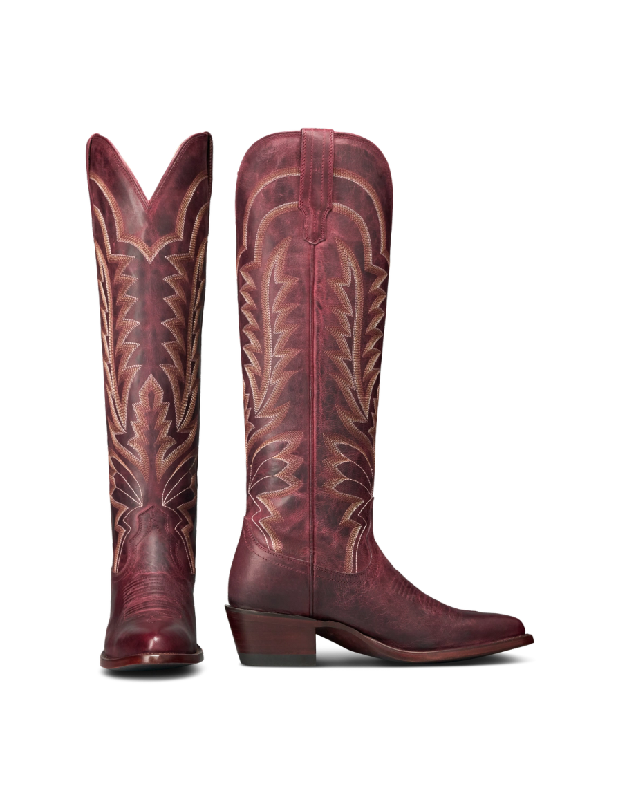 The Abby in Wine Goat. A pair of tall, burgundy leather cowboy boots from The Abby Goat, featuring decorative stitching and pointed toes, shown side by side on a white background.
