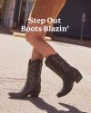 Person walking on a sunny street wearing black cowboy boots with decorative stitching. Text overlay reads, "Step Out Boots Blazin'".