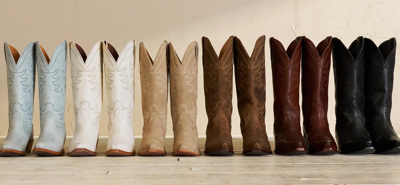 Array of colorful cowboy boots displayed against a neutral wall with a shadow.