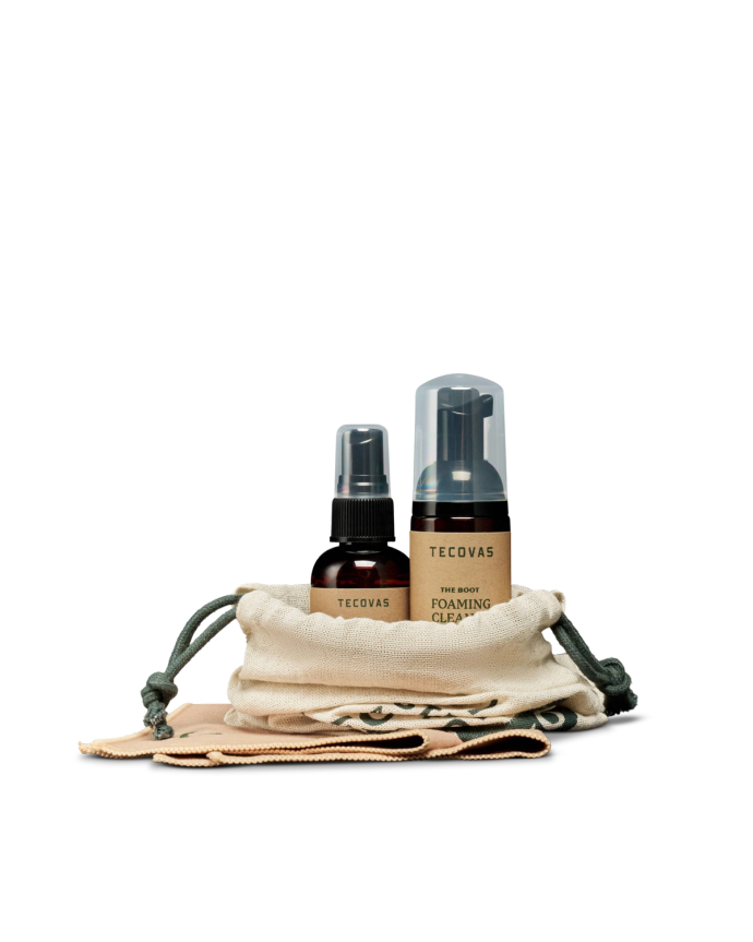 Two Tecovas shoe care products—a spray bottle and a foaming cleaner—are displayed upright in a small drawstring pouch with two cloths on a white background.